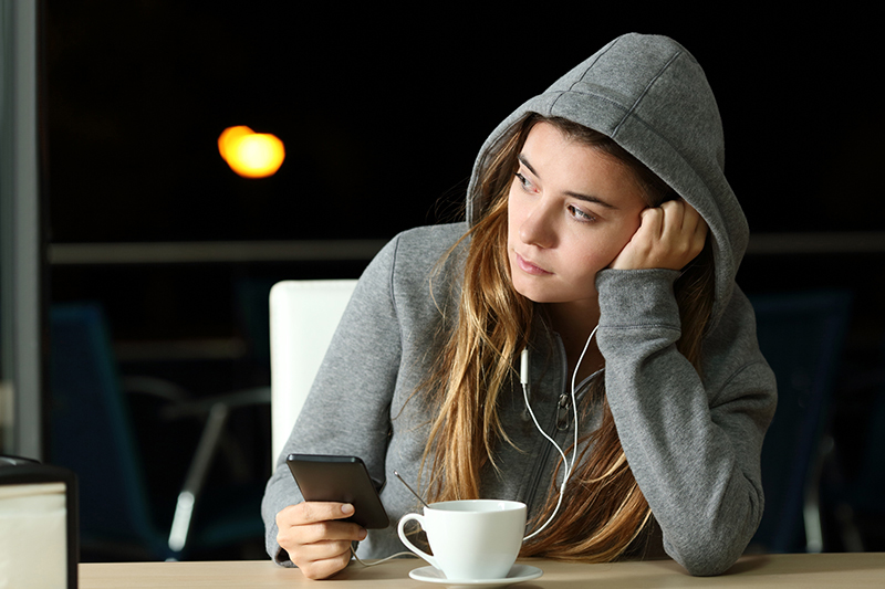 teenager in hoodie listening to music at a coffee shop